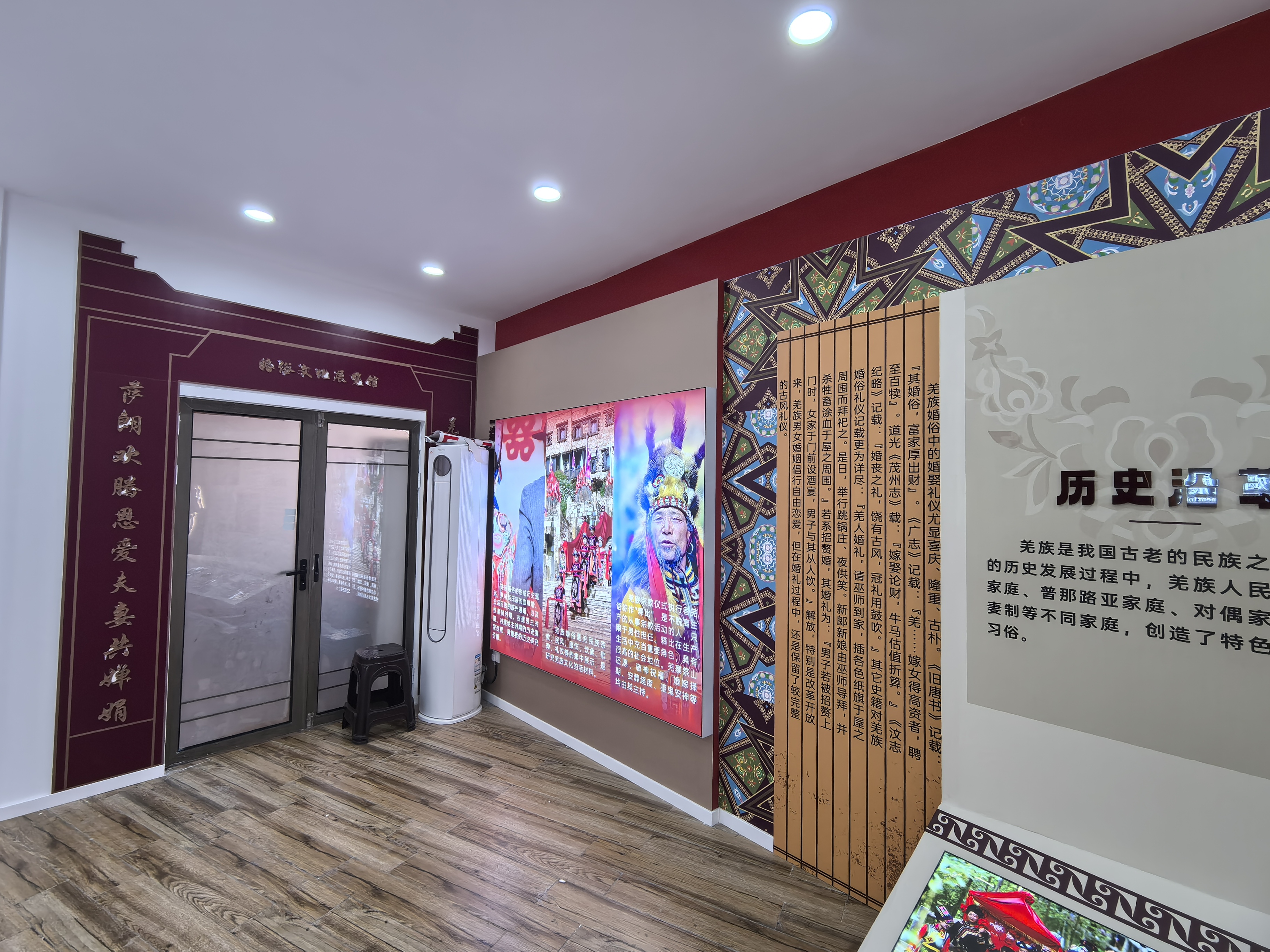 羌族婚俗发展史展览室入口,墙面介绍羌族婚俗历史沿革与文字说明,中央平面灯箱画面展示羌族传统婚礼场景